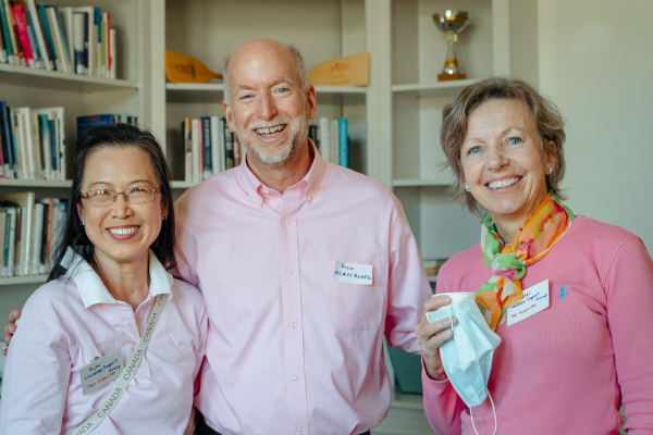 a man standing with two woman. all wearing pink