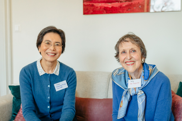 two woman both wearing blue smiling.